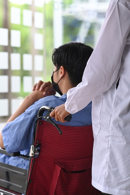 Cropped shot nurse pushing her patient on wheelchair.