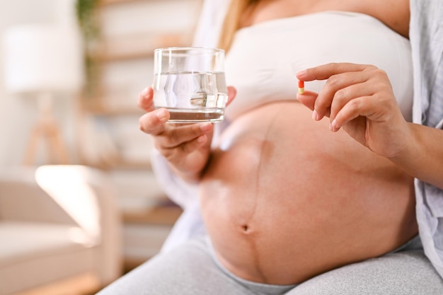 Cropped shot of a pregnant woman holding a glass of water and a vitamin pill motherhood