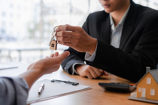 Cropped shot of real estate agent or banker giving a key to his customer.