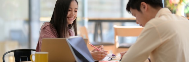 Cropped shot of two university students sitting in modern coffee shop