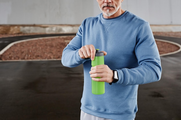 Cropped shot of unrecognizable senior man holding water bottle during outdoor workout in urban setti