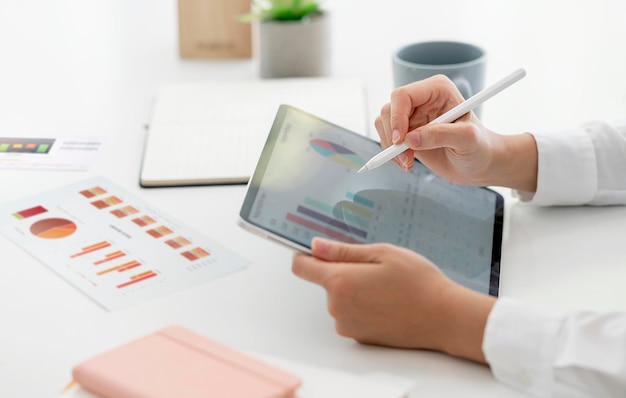 Cropped shot of woman hand using digital pen and portable tablet analyzing business graph report. Business strategy and planning concept.