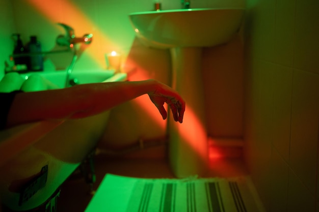 Cropped shot of woman relaxing in bathtub in neon light suffering from opioid use disorder