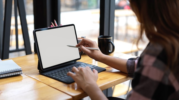 Cropped shot of woman using blank screen tablet in comfortable working space