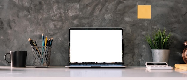 Cropped shot of workspace with mockup laptop with white blank screen Home interior or office background