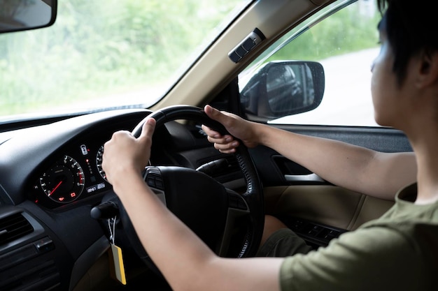 Cropped shot of young asian man driving car