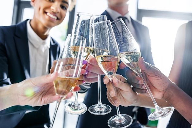 Cropped shot of young business colleagues drinking champagne in office