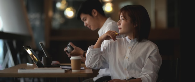 Cropped shot of young businesswoman thinking about her project while sitting next to her colleague