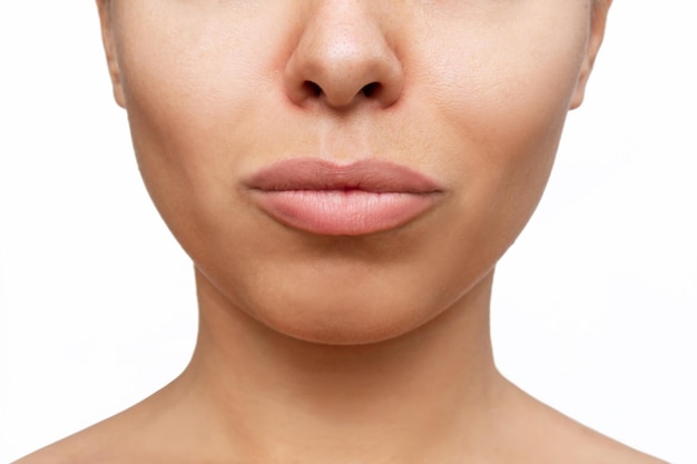 Cropped shot of young caucasian woman's face with lips after lip enhancement on a white background