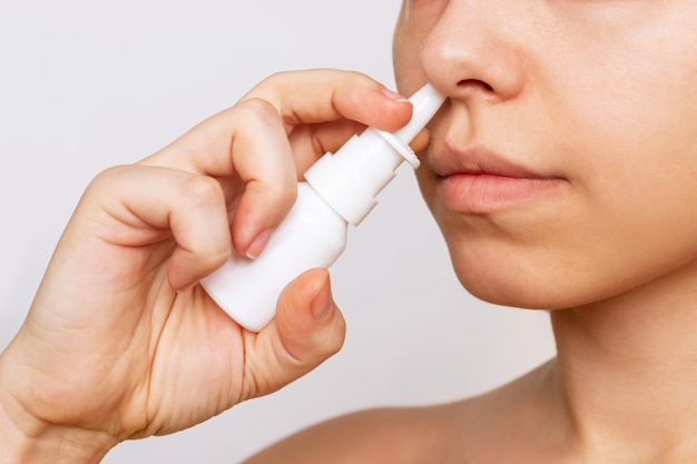 Cropped shot of a young caucasian woman using nasal spray for a runny nose and congestion