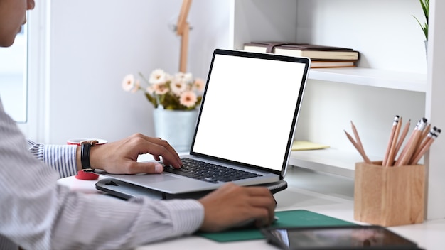 Cropped shot of young man hands using laptop search information on his workspace at home office room.