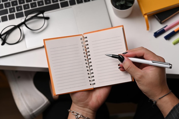 Cropped shot young man holding pen and writing on empty notebook