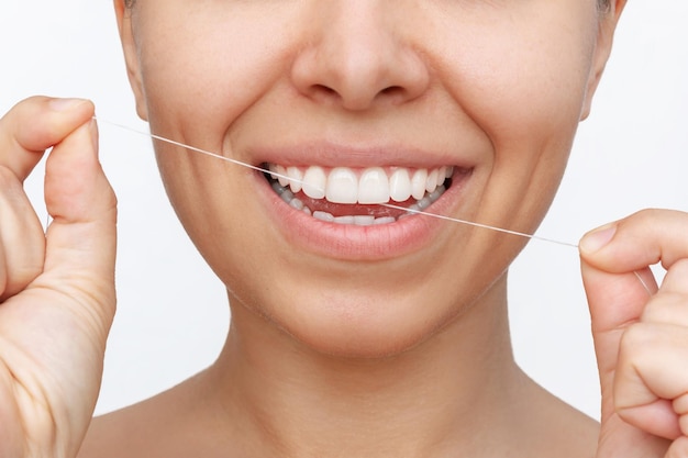 Cropped shot of a young woman flossing her teeth after meal with dental floss. Dental health care