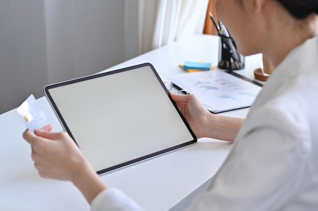 Cropped shot young woman holding credit card and using digital tablet.