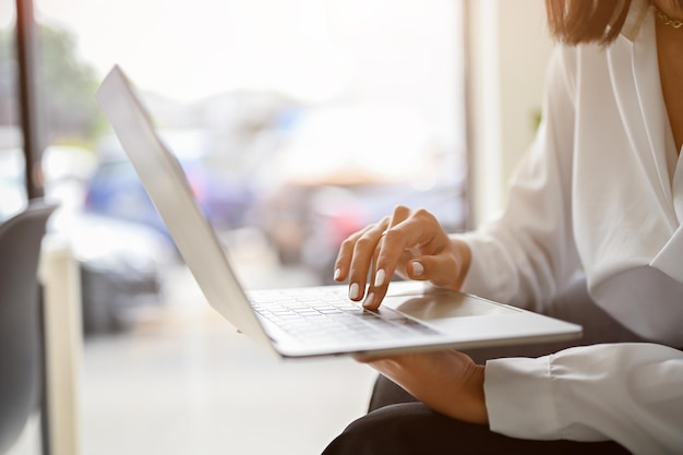 Cropped side view image of a businesswoman using her laptop typing on keyboard