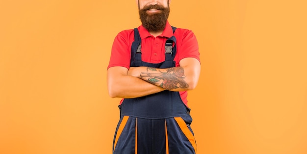 Cropped smiling man technician in work clothes on yellow background