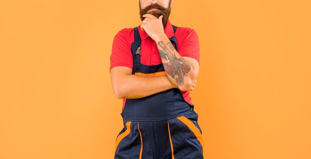 Cropped thinking man loader in work clothes on yellow background