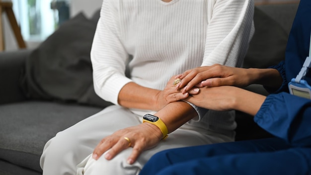 Cropped view of female caregiver taking care of elderly woman during home care visit Elderly healthcare concept