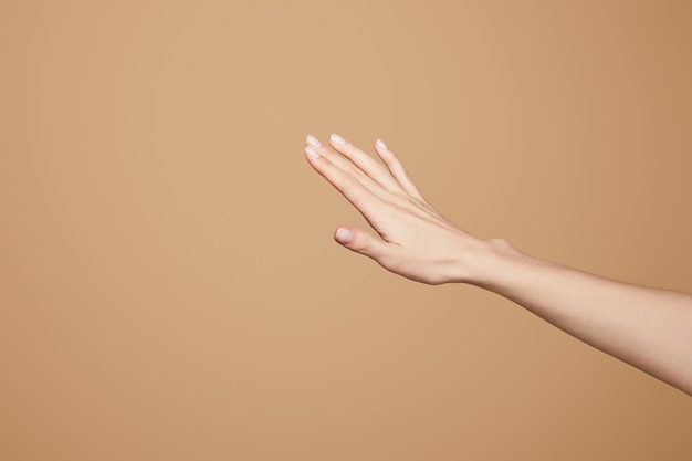 Cropped view of female delicate hand isolated on beige