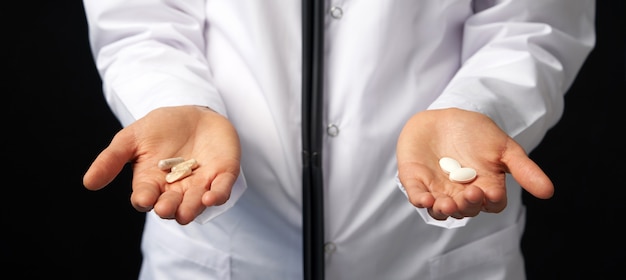 Cropped view of female Doctor holding in hands Pills to choose. Difficult Choice between drugs. Placebo drugs concept. Healthcare concept.