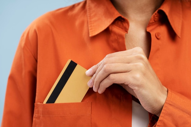 Cropped view of female hand putting credit card on the shirt pocket isolated over blue background