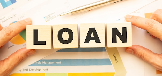 Cropped view of hands holding wooden cubes with LOAN lettering on work table