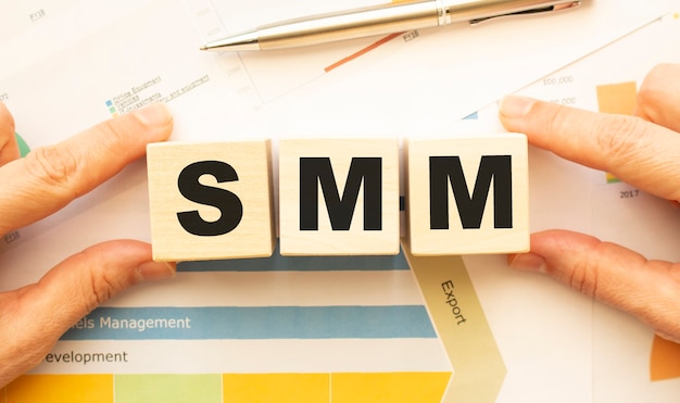 Cropped view of hands holding wooden cubes with SMM lettering on work table