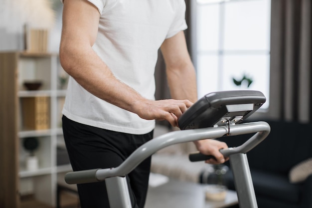 Cropped view of male hands tapping on screen of control panel of treadmill