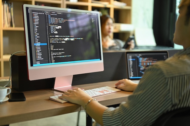 Cropped view male software developer checking mistakes in programming code on computer screen