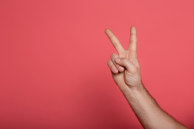 Cropped view of man showing peace sign on pink