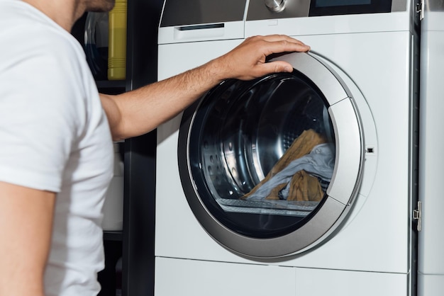 Cropped view of man touching modern washing machine