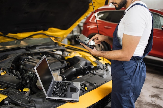 Cropped view of mechanic using tablet computer recording automobile engine checks