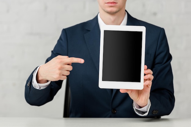 Cropped view of realtor in suit pointing with finger at digital tablet with blank screen on white