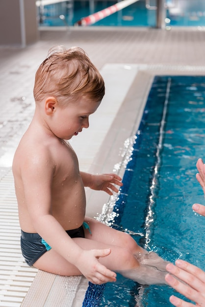 Cropped view of swim coach near cute toddler boy in swimming pool