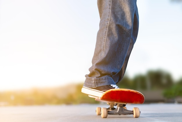 Cropped view of a young man skating on a skate park with black sneakers on a red skateboard