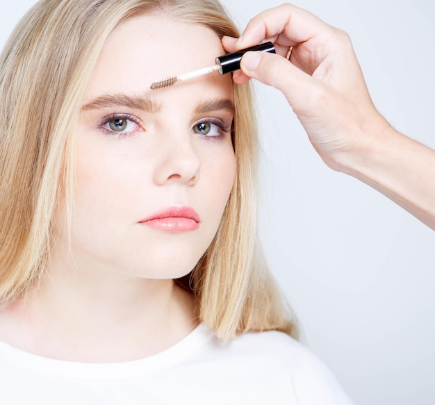 A cropped view of a young woman applying eyebrow gel a makeup artist makes eyebrows to a client