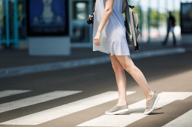 Cropped Young traveler tourist woman in light clothes with backpack standing on crosswalk at international airport