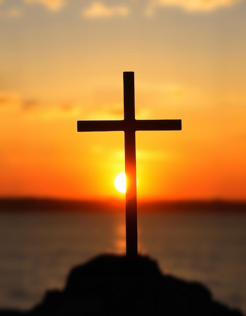 Photo a cross is on a rock in front of a sunset