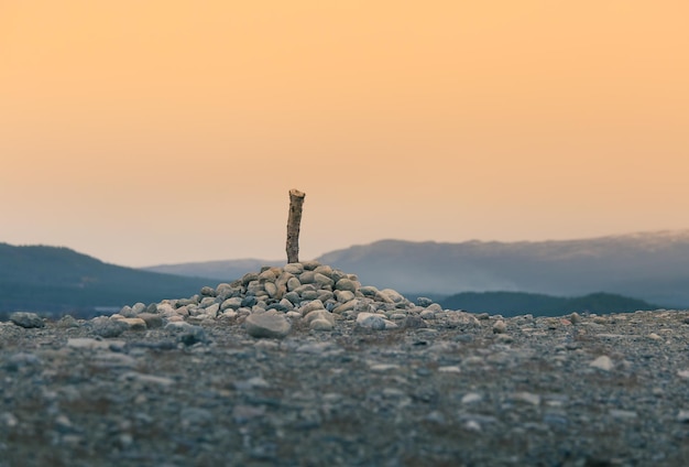 Photo cross on rock against sky during sunset