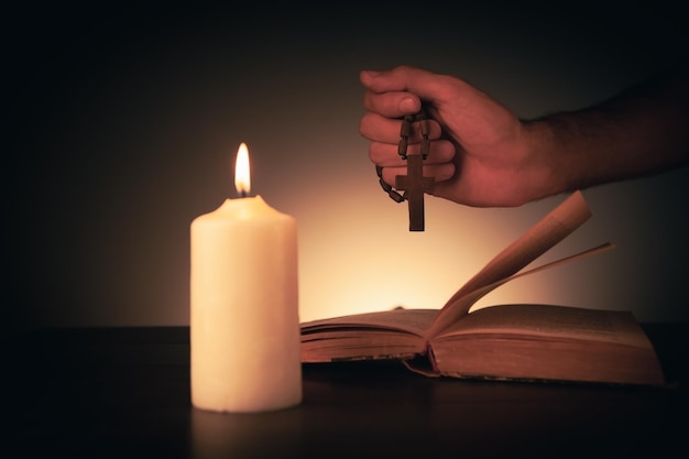 Cross with bible and candle on a wooden table