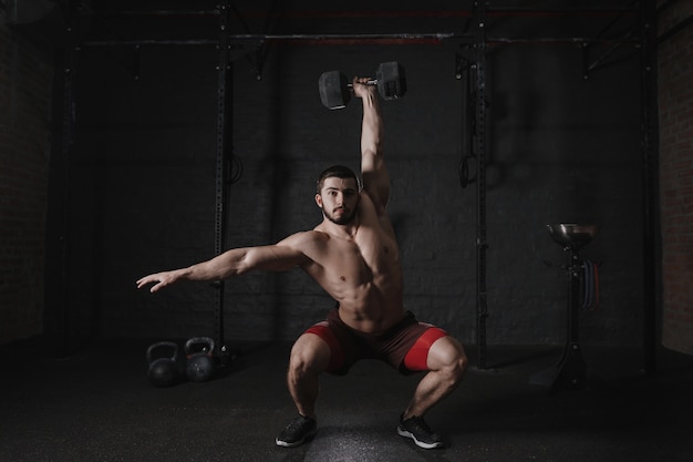 Crossfit athlete doing overhead dumbbell squats at the gym