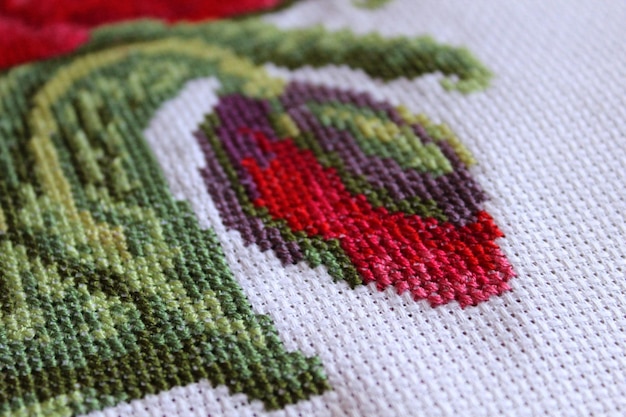 Photo crossstitch poppies on a white canvas closeup selected focus