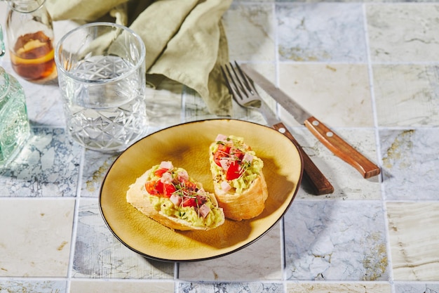 Crostini or bruschetta with softened avocado ham and tomatoes toast with mashed avocado