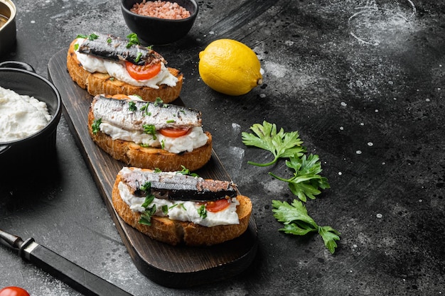 Crostini with fish and ricotta on black dark stone table background with copy space for text