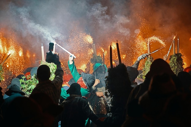 A crowd of people in green and black are throwing fire sparks into the air La Patum