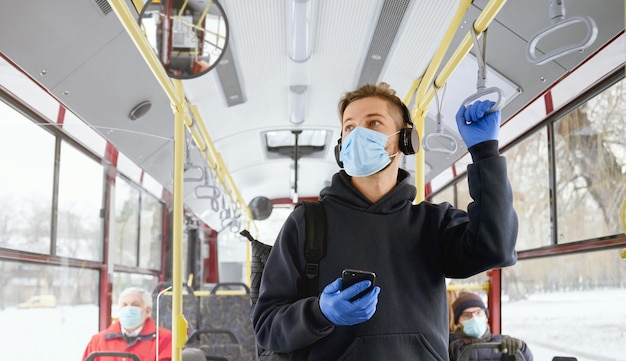 Crowd of people traveling by bus wering medical masks and gloves during global pandemic