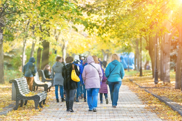 Crowd of people walking in the autumn city park