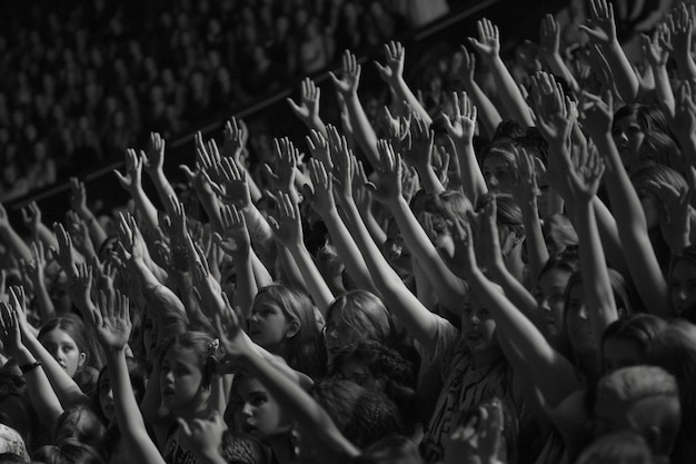 Photo crowd of people with raised hands at a concert black and white