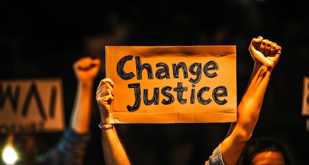 Photo crowd protesting at night holding up a change justice sign