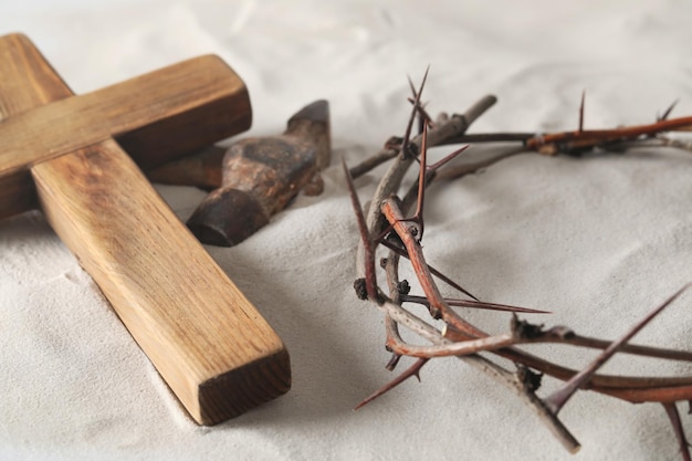 Crown of thorns wooden cross and hammer on sand Easter attributes